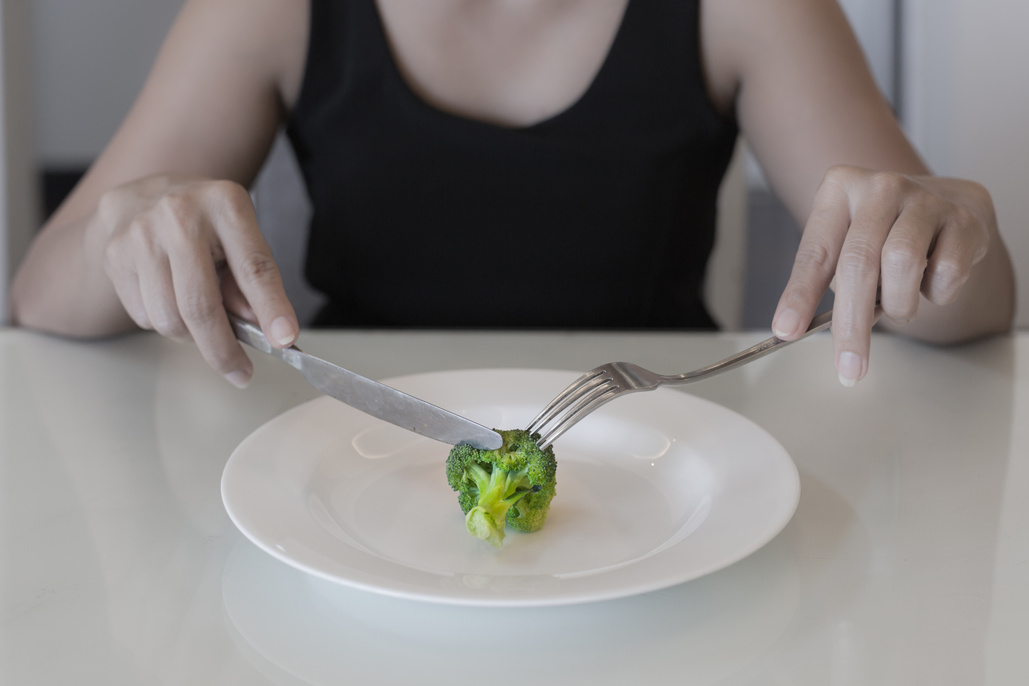 A hungry woman on a weight loss diet. Empty plate with a vegetable. Low calorie diet.